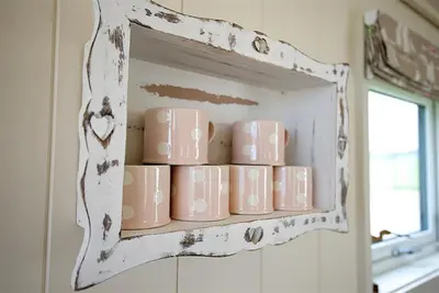 a shelf with a bunch of pink mugs on it at Barley Lodge in Girthon