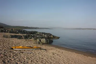 a yellow kayak sitting on a beach next to the water at Barley Lodge in Girthon