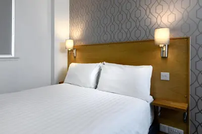 a bed with white sheets and pillows in a room at Corner House Hotel in Annan