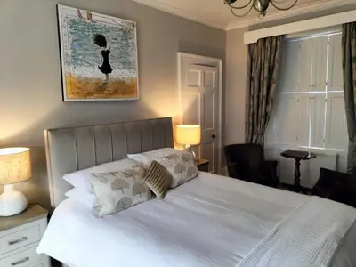 a bedroom with a bed with white sheets and pillows at Park Cottage - Spacious & Luxurious Room in B Listed Cottage in Moffat