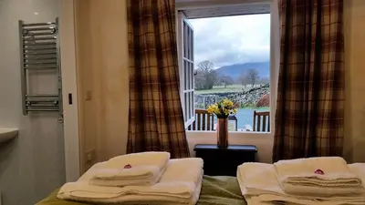 a room with a window with towels on a bed at Lake District, Mountain Views, Accessible Studio Bothy in Borrowdale Valley