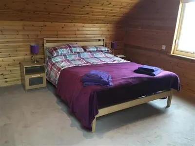 a bedroom with a large bed in a log cabin at Calluna Cottage in Rockcliffe