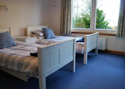a bedroom with two beds and a window at Calluna Cottage in Rockcliffe