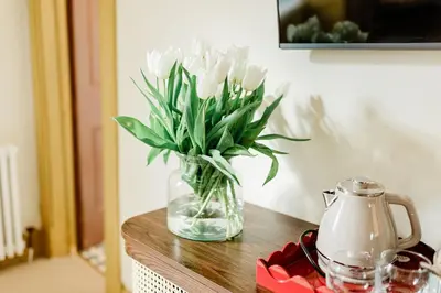a vase of white flowers sitting on a table at Bedroom 2 - Rockcliffe in Dumfries