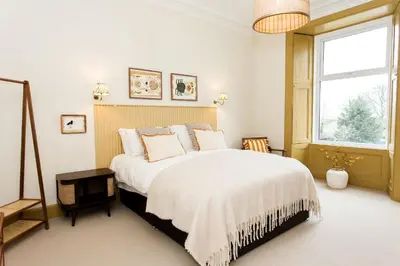a bedroom with a large bed with white sheets and a window at Bedroom 2 - Rockcliffe in Dumfries