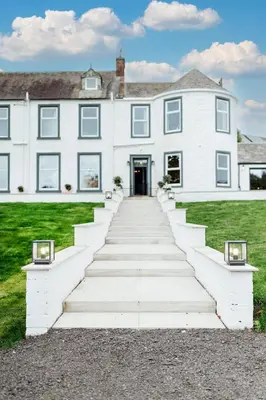 a white house with a staircase leading up to it at Bedroom 2 - Rockcliffe in Dumfries