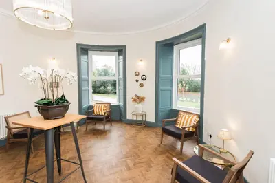 a living room with a table and chairs and windows at Torr House Hotel in Dumfries