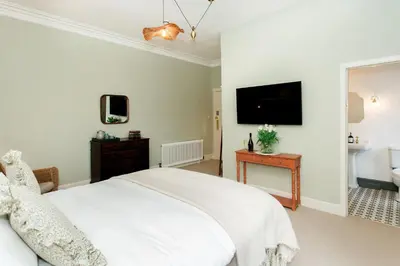 a bedroom with a white bed and a tv on the wall at Torr House Hotel in Dumfries