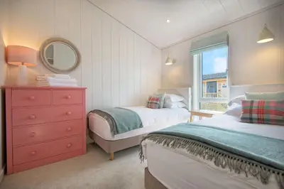 a bedroom with two beds and a dresser and a window at Clover Lodge in Gatehouse of Fleet