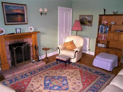 a living room with a chair and a fireplace at Colbeine in Rockcliffe