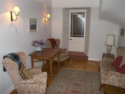 a living room with chairs and a table and a door at Colbeine in Rockcliffe