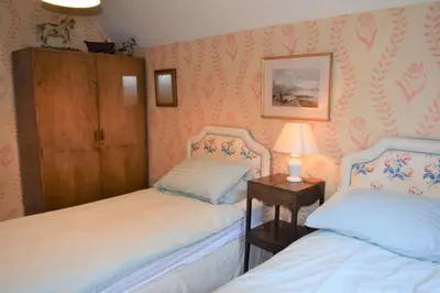 a bedroom with two beds and a table with a lamp at Craigrathan in Kippford