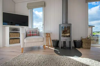 a living room with a fireplace and a chair at Crabtree Lodge in Girthon