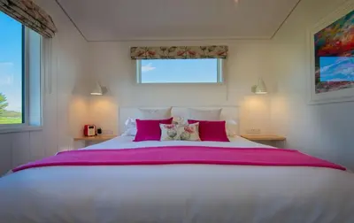 a bedroom with a large white bed with pink pillows at Crabtree Lodge in Girthon
