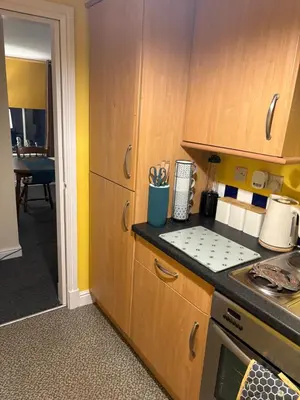 a kitchen with wooden cabinets and a counter top at Maryport town centre cosy home in Maryport