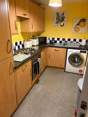 a kitchen with wooden cabinets and a washer and dryer at Maryport town centre cosy home in Maryport