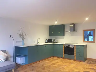 a kitchen with green cabinets and a couch in a room at Holly Lodge, Gilchristland Organic Farm cottage in Closeburn
