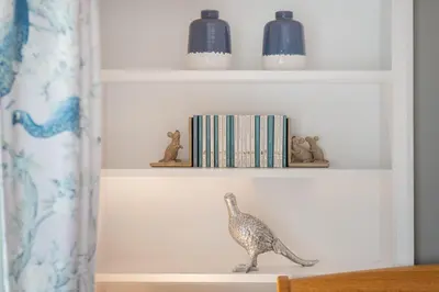 a bird figurine on a shelf with books at Cozy Lake District House on the fells in Ambleside