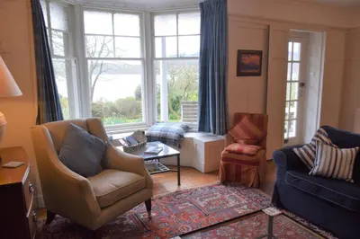 a living room with a couch and chairs and a window at Elm Cottage in Kippford