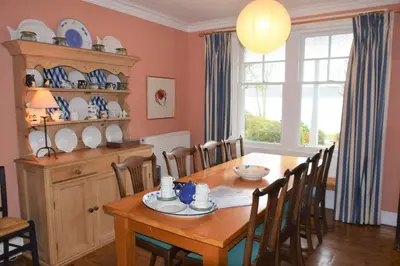 a dining room with a wooden table and chairs at Elm Cottage in Kippford