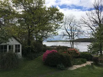 a house with a yard with flowers and a lake at Elm Cottage in Kippford