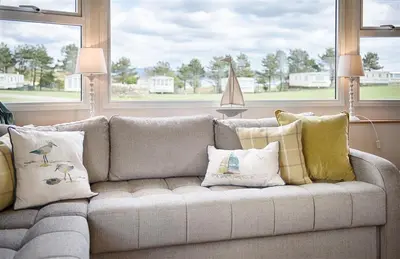 a couch with many pillows on it in a living room at Konkers in Girthon