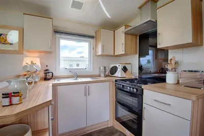a kitchen with white cabinets and a black stove top oven at Konkers in Girthon