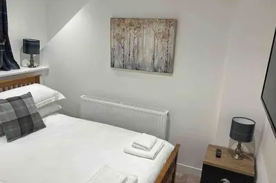 a bedroom with a bed and a painting on the wall at Modern cottage with hot tub in Kirkcudbright