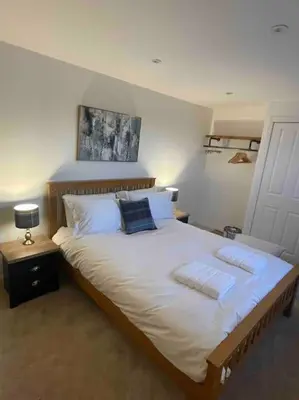 a bedroom with a large bed with white sheets and pillows at Modern cottage with hot tub in Kirkcudbright