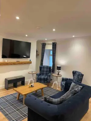 a living room with a blue couch and chairs at Modern cottage with hot tub in Kirkcudbright