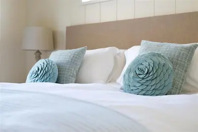 a white bed with blue pillows on it at Granary Lodge in Girthon