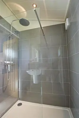a shower with a glass door and a sink at Granary Lodge in Girthon