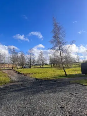 an empty road with a tree in a field at Highland Hideaway in Wigton