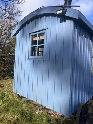 a blue shed with a window on a hill at Highland Hideaway in Wigton