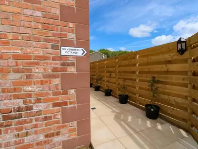 a brick wall with potted plants and a sign on it at Silverbirch Cottage - 3 Bedrooms - Sleeps 6 in Frizington
