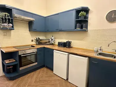 a kitchen with blue cabinets and a wooden counter top at Sea Ayr - City Centre Apartment in Ayr