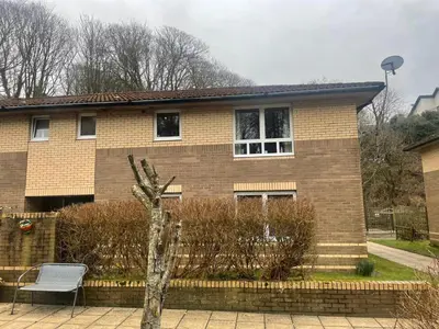 a brick house with a chair in front of it at Portpatrick 2 bedroom Self Catering Flat in Portpatrick