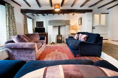 a living room with two couches and a fireplace at Bridge End Cottage Elterwater in Ambleside