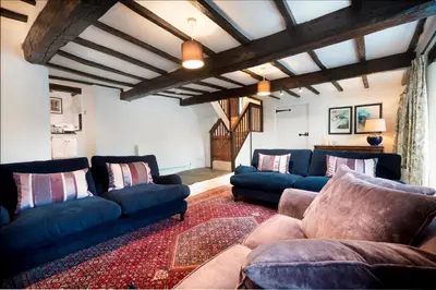 a living room with two blue couches and a rug at Bridge End Cottage Elterwater in Ambleside
