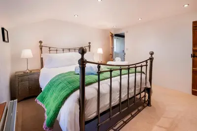 a bedroom with a bed with a green blanket at Bridge End Cottage Elterwater in Ambleside
