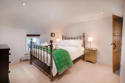 a bedroom with a bed with a green blanket at Bridge End Cottage Elterwater in Ambleside