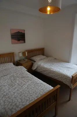 a bedroom with two beds and a lamp at Chaucer View, Chaucer House Apts in Keswick