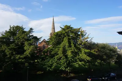 a church with a steeple and trees in front of it at Chaucer View, Chaucer House Apts in Keswick