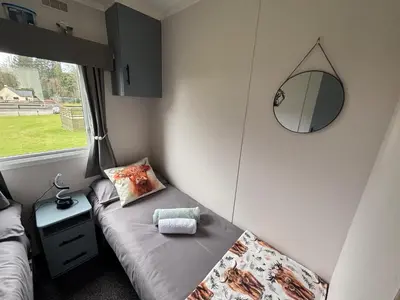 a small room with a bed and a mirror at No 38 Heilan Hoose at Three Lochs Newton Stewart in Newton Stewart