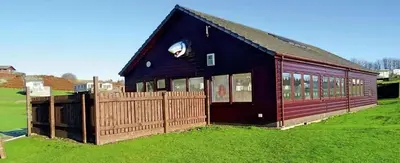 a black building with a wooden fence in a field at No 38 Heilan Hoose at Three Lochs Newton Stewart in Newton Stewart