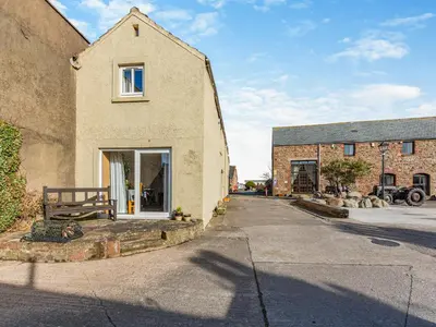 a brick house with a bench next to a street at Turnip House - Uk48909 in Allonby