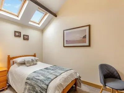 a bedroom with a bed and a chair at Turnip House - Uk48909 in Allonby