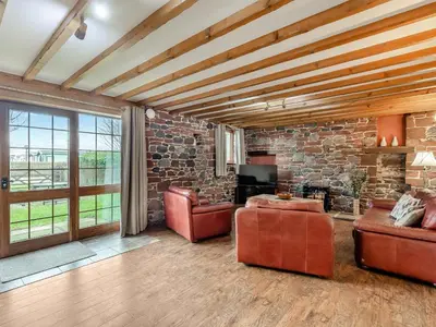 a living room with leather furniture and a stone wall at Barley Store - Uk48910 in Allonby
