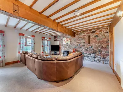 a living room with a leather couch in a stone wall at Engine House - Uk48912 in Allonby
