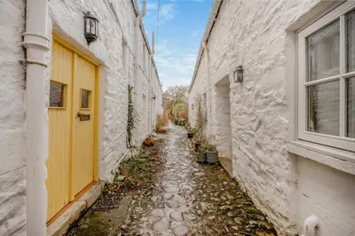 an alley between two buildings with a yellow door at 2 Bed in Kirkcudbright oc-a30803 in Kirkcudbright